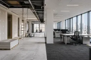 Espace de bureau moderne en cours de rénovation avec une zone en travaux et une zone occupée fonctionnelle, illustrant un chantier en site occupé à Paris