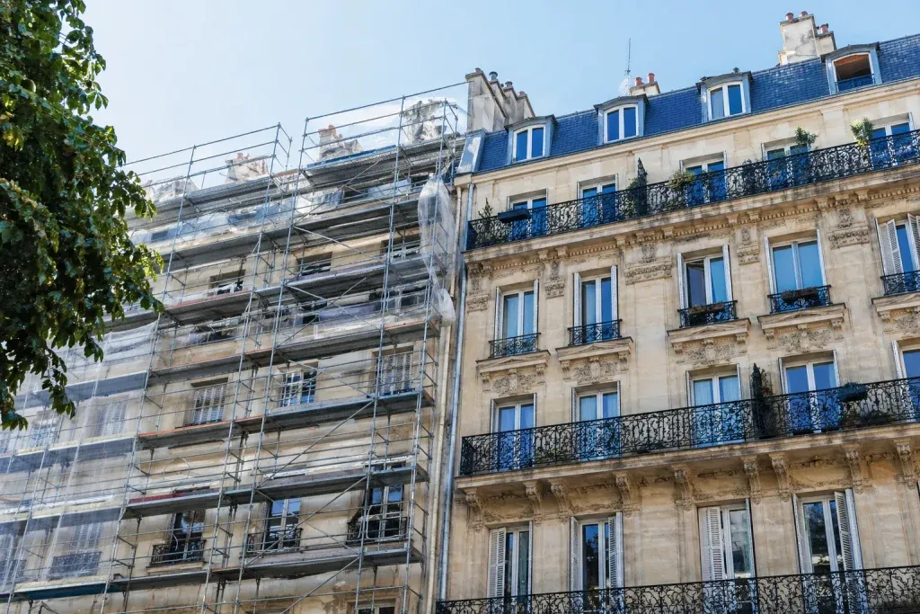 Immeuble parisien avec façade haussmannienne en rénovation, échafaudage installé pour des travaux de copropriété en milieu urbain